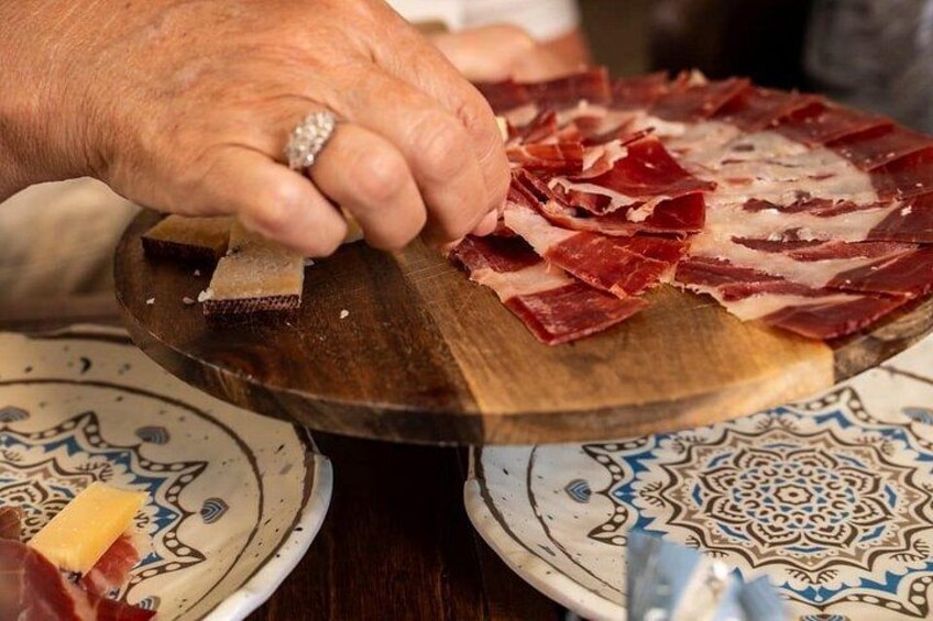 Una persona cortando embutido en una tabla de madera. 1