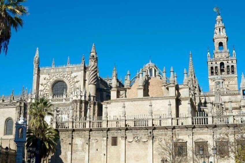 Een historische kathedraal met gedetailleerde gotische architectuur, een opvallende klokkentoren en een heldere blauwe lucht. 3