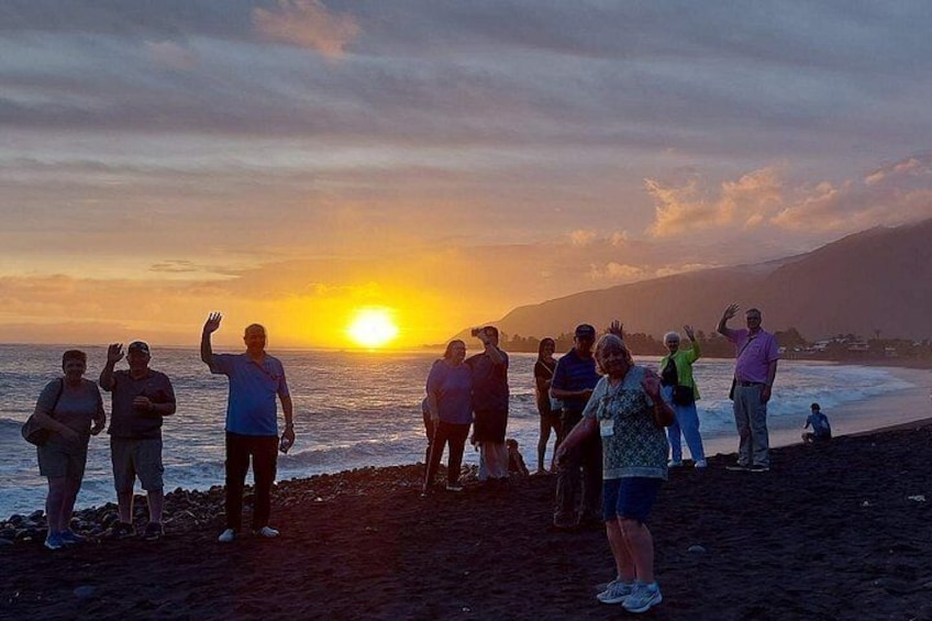 A group of people standing on a beach at sunset. 5