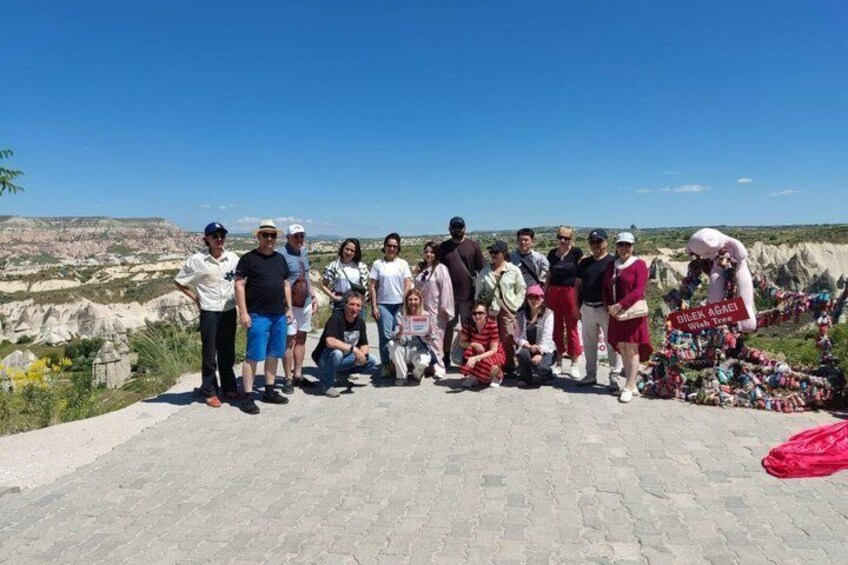 Un groupe de personnes se tient sur une surface pavée, avec un paysage rocheux en arrière-plan. 2