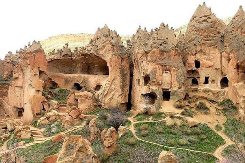Formación rocosa con viviendas excavadas en la roca y un sendero sinuoso. 4
