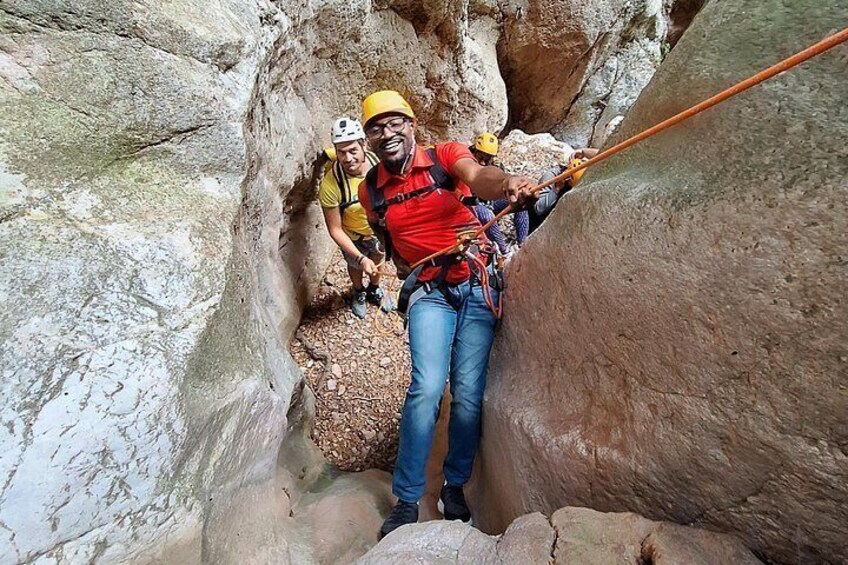 A person rappelling down a rocky canyon with a rope. 3