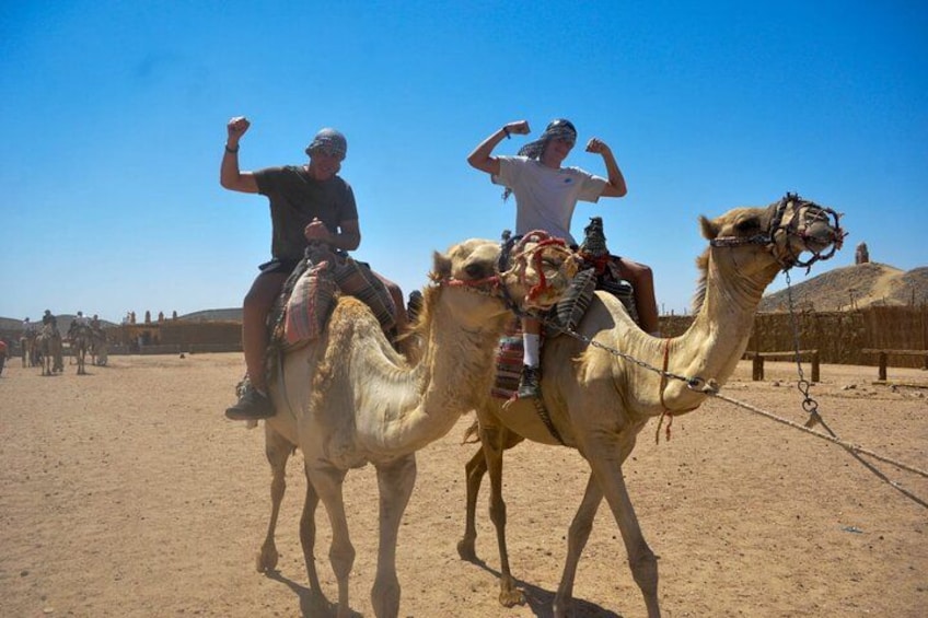 Two camels with riders in a desert setting. 3
