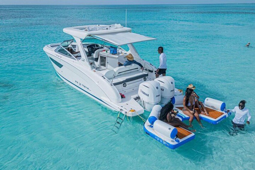 A white boat with a canopy and inflatable seating on turquoise water. 1