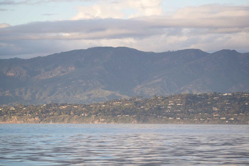 A coastal landscape with mountains in the background and a body of water in the foreground. 3