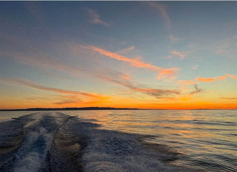 A boat's wake on calm water during sunset. 2