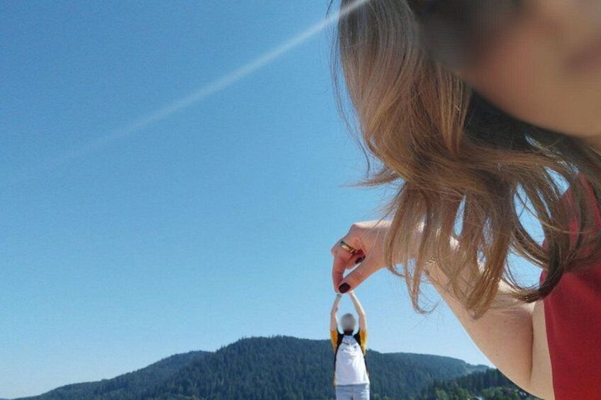 A person holding a camera with a mountain in the background. 3