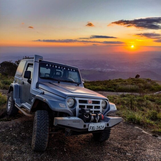 A silver off-road vehicle with a license plate 'FXL-3424' parked on a dirt path with a sunset in the background. 5