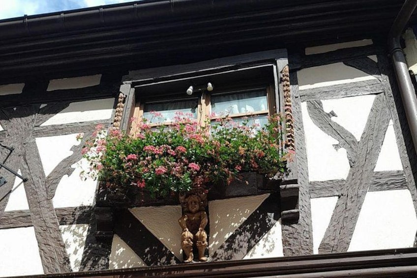 Ein Fachwerkhäuschen mit einem Blumenkasten voller rosa Blüten. 5