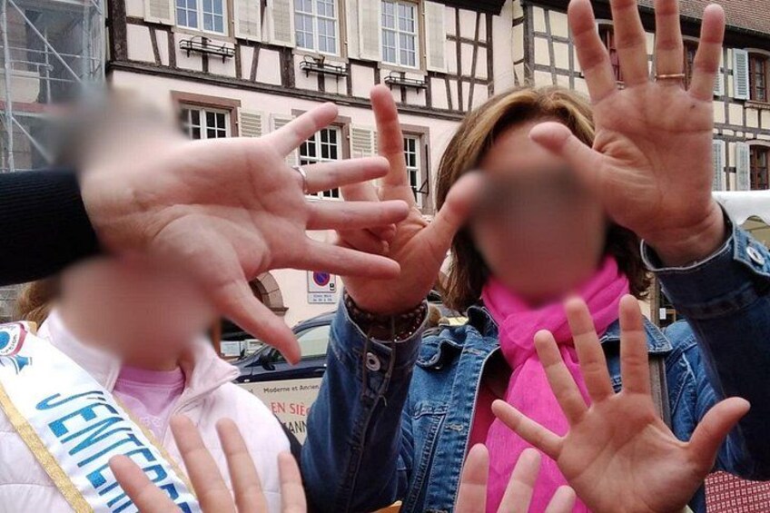 Eine Gruppe von Personen mit erhobenen Händen vor einem Gebäude mit freiliegenden Fachwerkkonstruktionen. 2