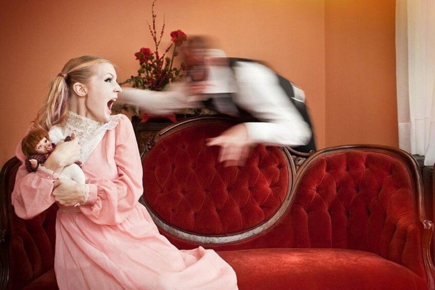 A person in a pink dress sitting on a red velvet sofa with a child. 3