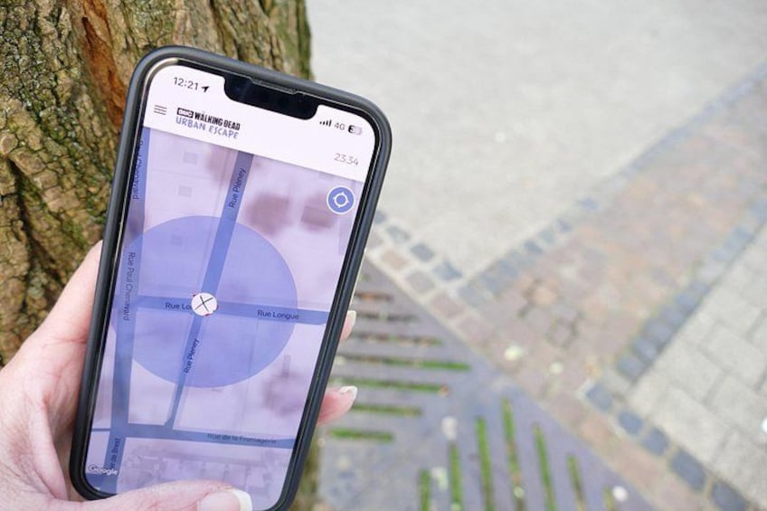 Un smartphone affiche une carte intitulée « Évasion urbaine dans l’univers de The Walking Dead » et l’heure 12h21. 1