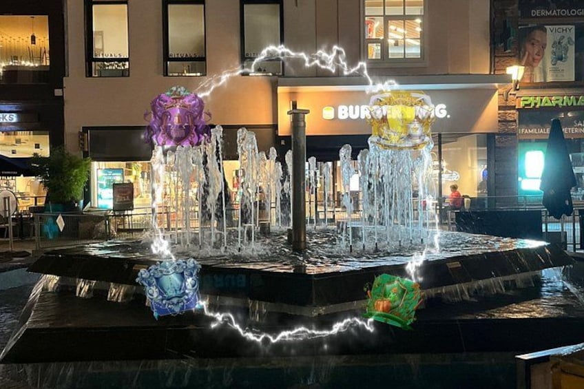 A fountain with water jets and colorful sculptures in an urban setting. 2