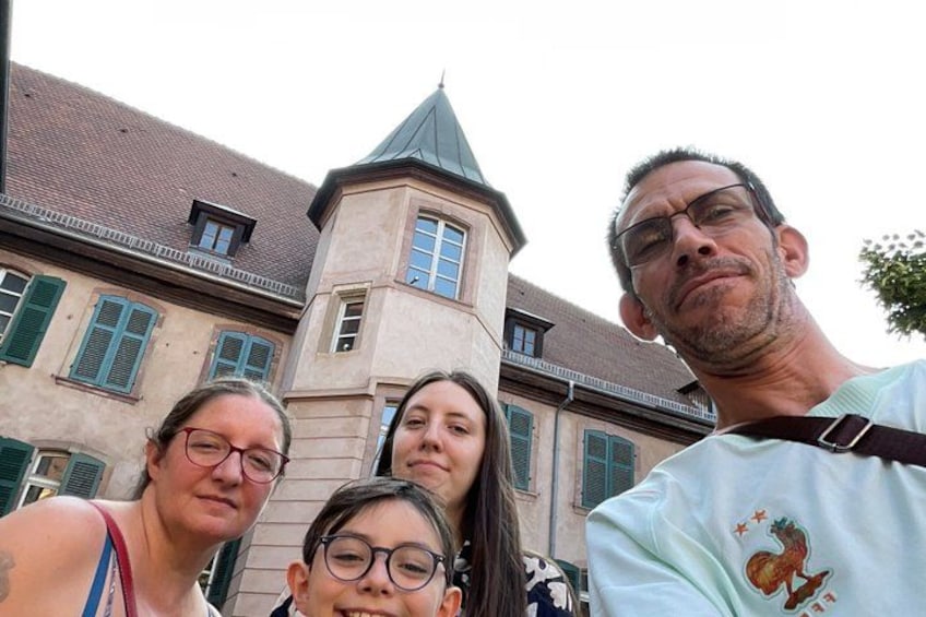 Un edificio storico con una torre, persiane verdi e una persona con una camicia azzurra e un emblema a forma di gallo. 3