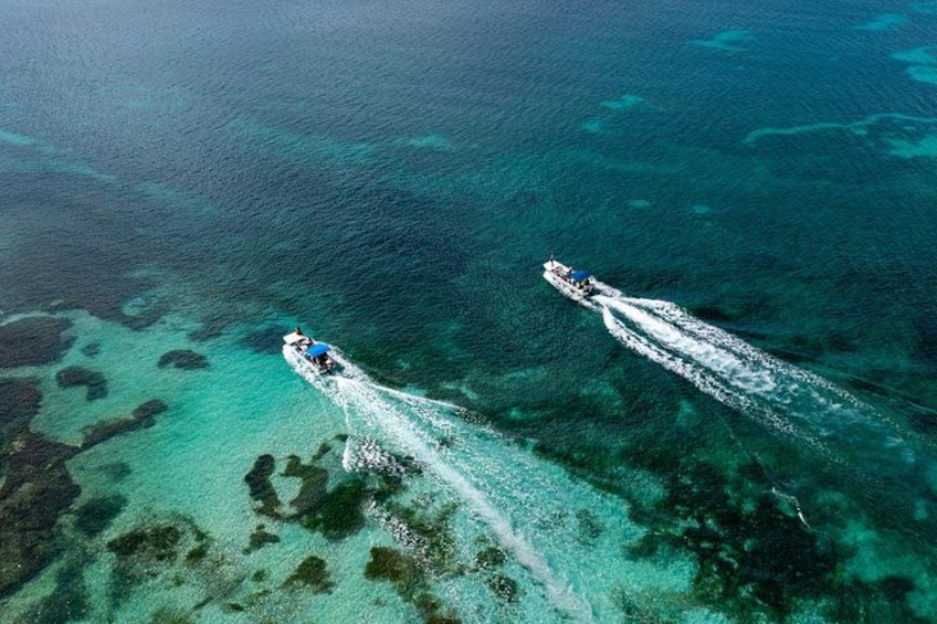 Two boats on a clear blue sea with shallow areas and coral reefs. 4