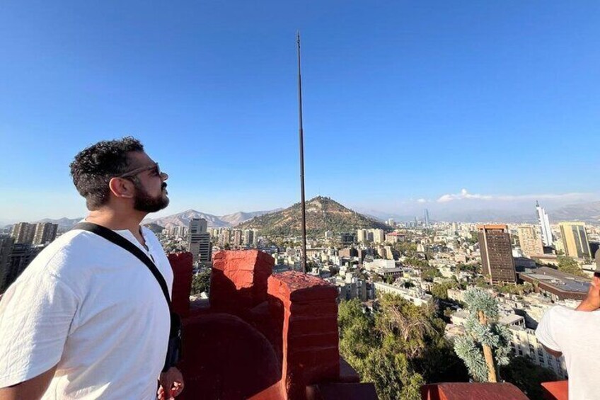 A person overlooking a cityscape with a prominent tower and a mountain in the background. 3