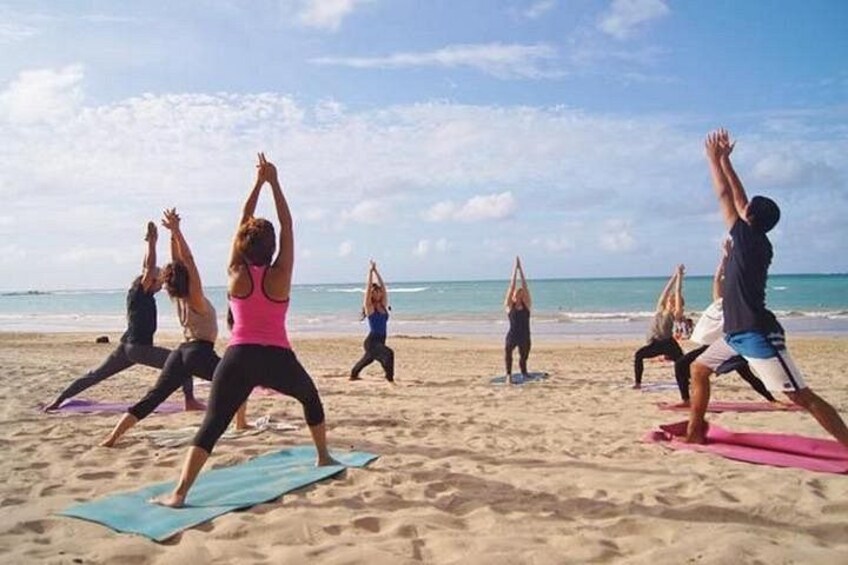 A group of people performing yoga on mats on a beach. 1