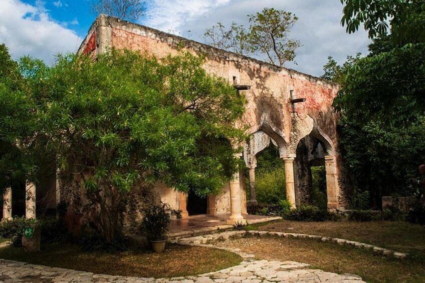 An ancient building with arches and columns, surrounded by greenery. 2