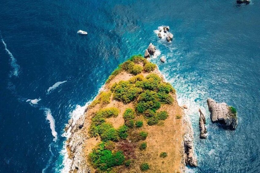 An aerial view of a coastal island with rocky outcrops and dense green vegetation. 3