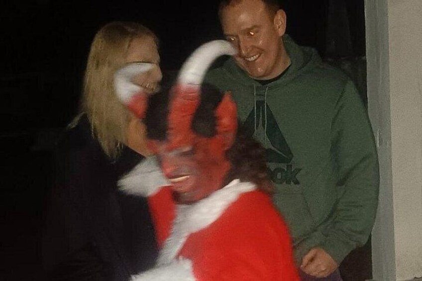 A person in a red and white costume with horns, standing next to a person in a green hoodie. 3