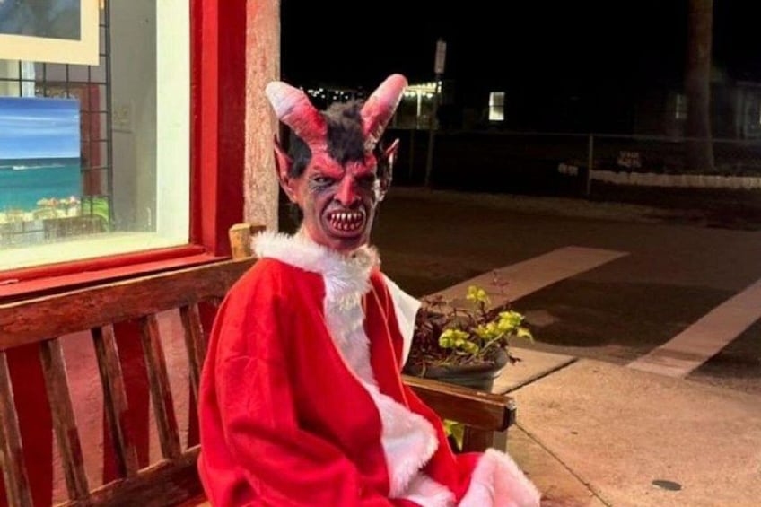A person in a red costume with horns sitting on a bench. 2
