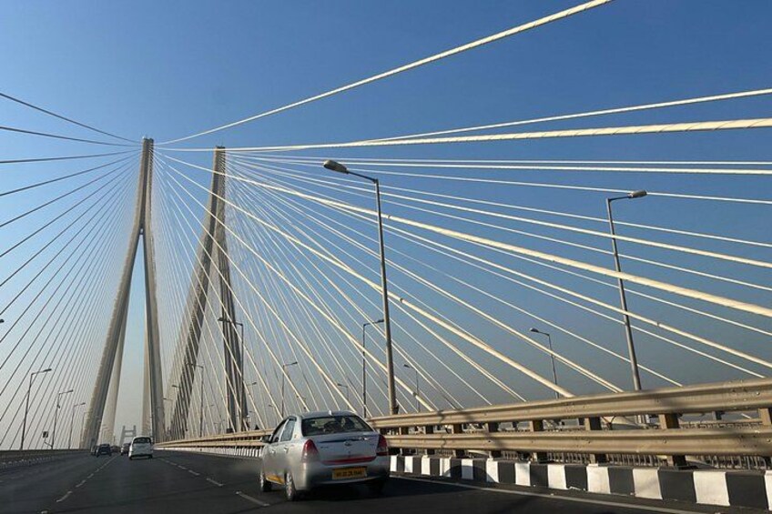 A cable-stayed bridge with multiple cables, a guardrail, and vehicles on the road. 4