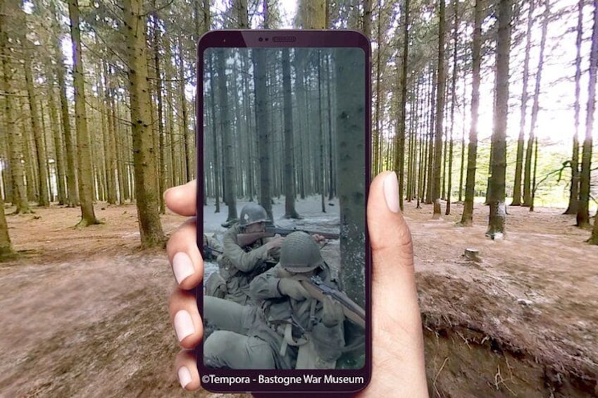 Une main tenant un téléphone intelligent sur lequel est affichée une photo de soldats dans une forêt. 5