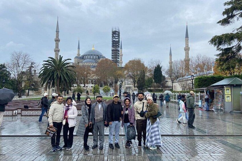 Un grupo de personas en una plaza pública, con una mezquita y minaretes al fondo. 5