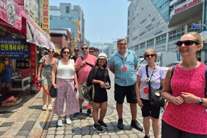 Un grupo de personas caminando por una calle de la ciudad, bordeada por tiendas y edificios. 2