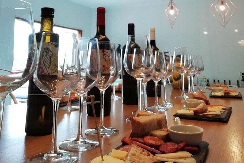A wine tasting setup with glasses, bottles, and cheese. 1