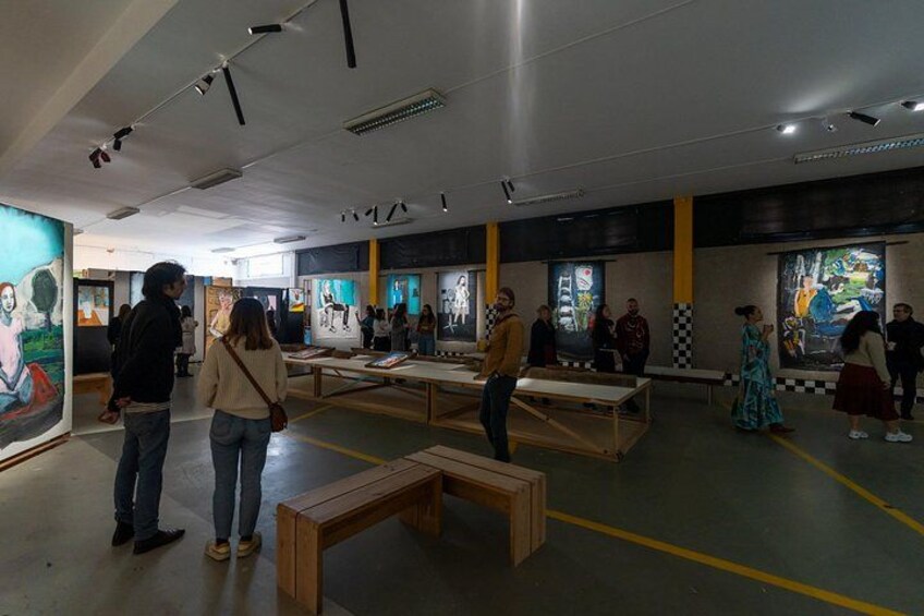 Ett konstgalleri med målningar på väggarna och träbänkar. 3