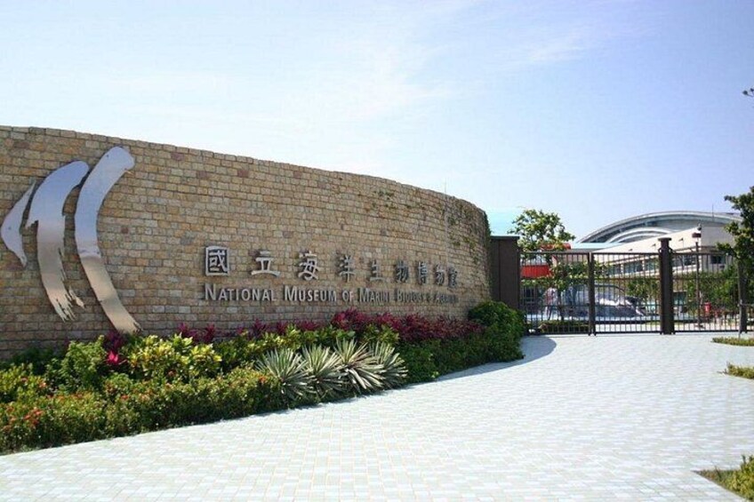 Un muro de ladrillo con una gran escultura de metal y el texto 'National Museum of Marine Life and Fisheries'. 1