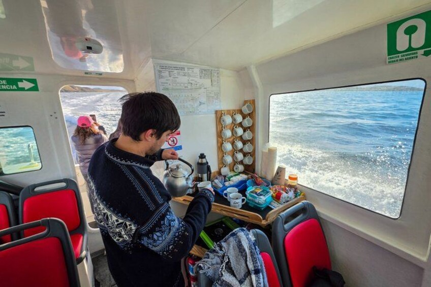 Una persona con suéter dentro de un vehículo, con una mesa que sostiene varios objetos y una ventana que muestra agua. 5