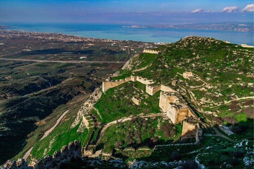 A mountainous landscape with a fortified structure and a coastal view. 4