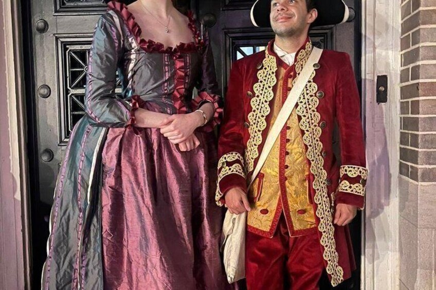 A person in a red and gold coat standing in front of a door. 2