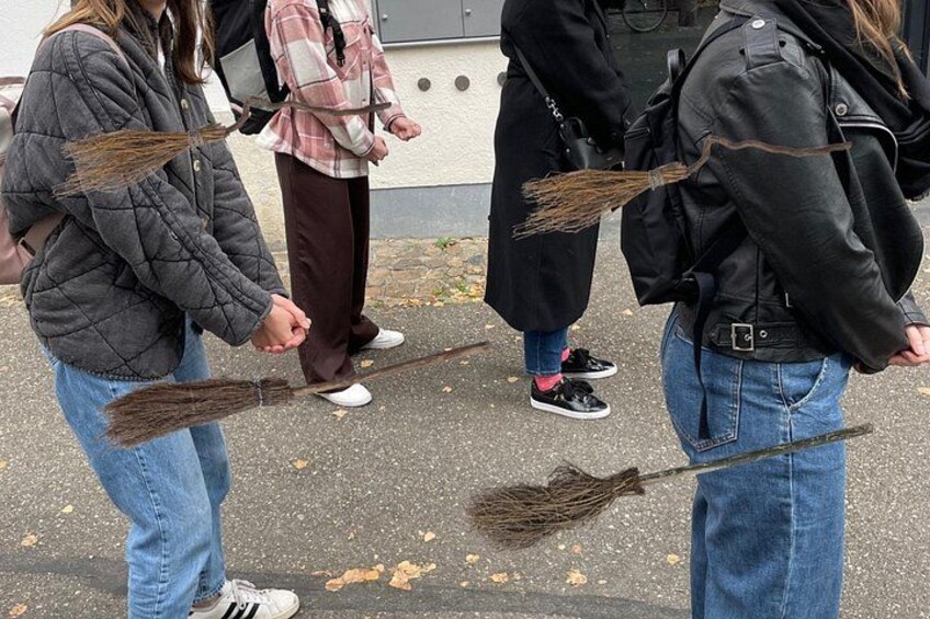Personer med koste står på en belagt overflade. 3