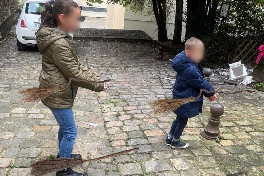 Une femme et un enfant jouent avec des balais dans une cour pavée. 3