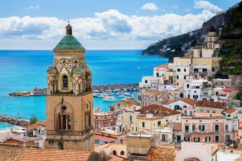 Una cittadina costiera con una torre imponente, edifici colorati e un mare cristallino. 1
