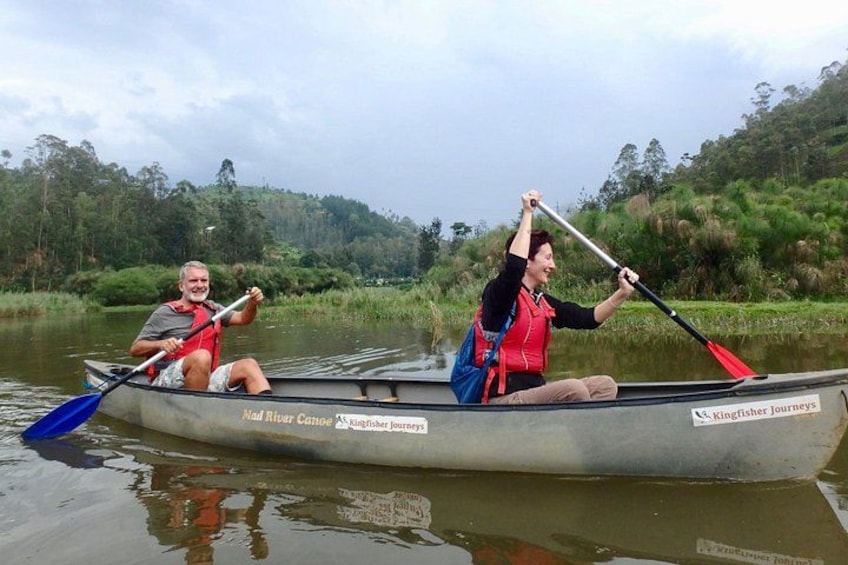 Dos personas remando en una canoa por un río con un paisaje boscoso al fondo. 4