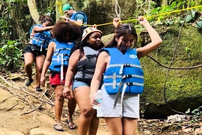Menschen mit Rettungswesten wandern auf einem Waldpfad. 2