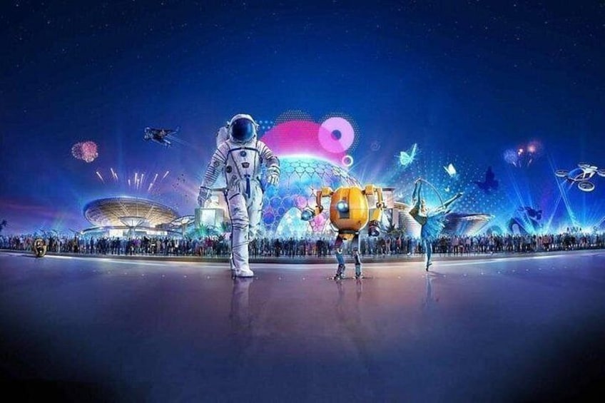 Un astronauta y un robot en un escenario con un público numeroso y un edificio futurista al fondo. 4