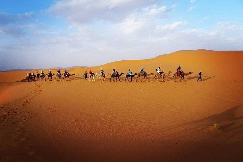 Un grupo de personas montando camellos a través de un paisaje desértico con dunas de arena. 1