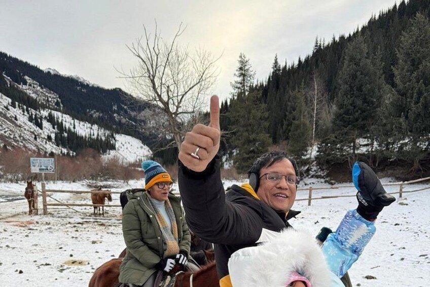 A snowy landscape with a person giving a thumbs-up, a horse, and a person riding a horse. 3
