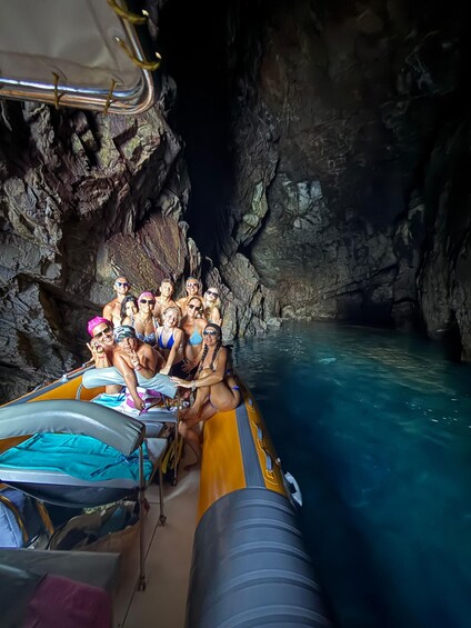 A group of people on a boat inside a cave with clear water. 4