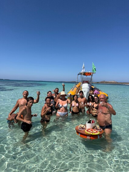 A group of people in shallow water with a boat and a table with food. 3