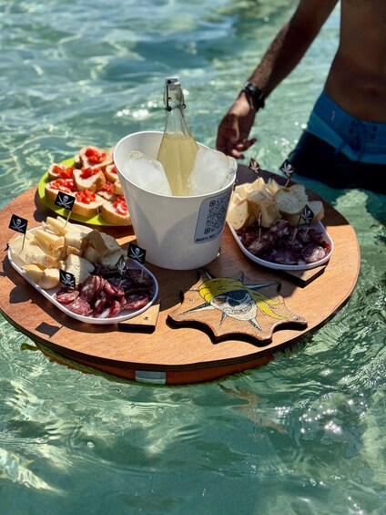 A wooden tray with food and drinks on a beach. 2