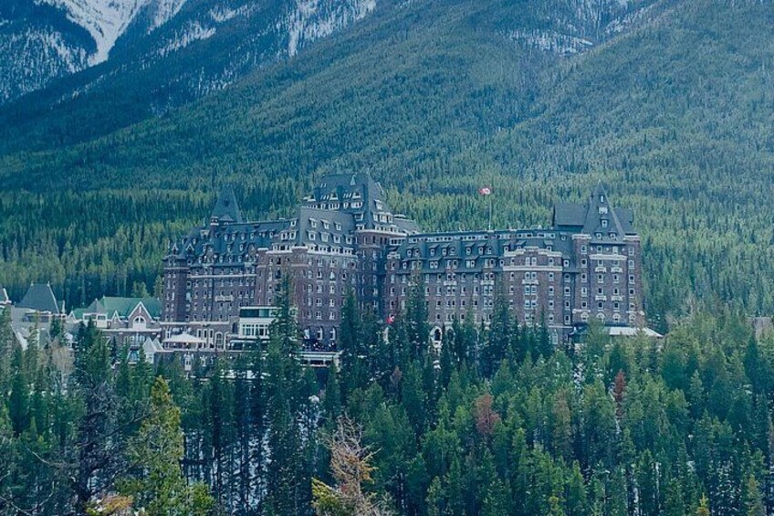 A large, historic building surrounded by dense forest and mountains. 4