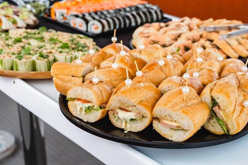 Una mesa de buffet con diversos alimentos, incluyendo sándwiches, sushi y otras tapas. 2