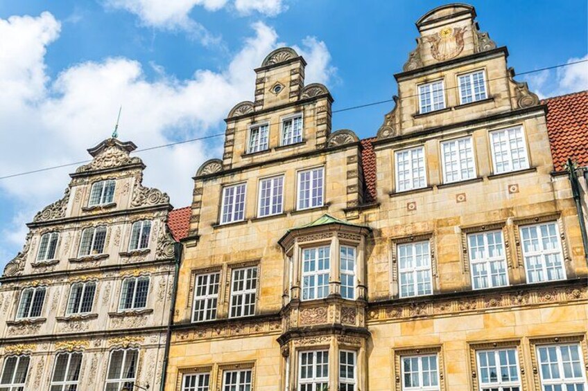 A row of historic buildings with ornate facades and red-tiled roofs. 1