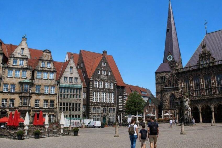 A historic town square with traditional buildings, a church, and a clear blue sky. 2